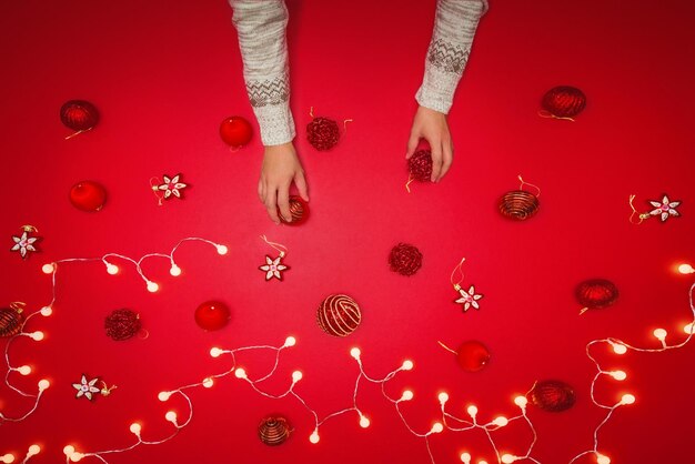 Cropped hand of woman holding christmas decoration on red background