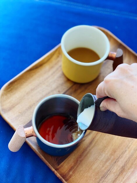 Cropped hand of woman holding coffee on table