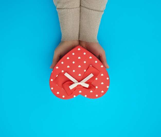 Photo cropped hand of woman holding gift box over blue background