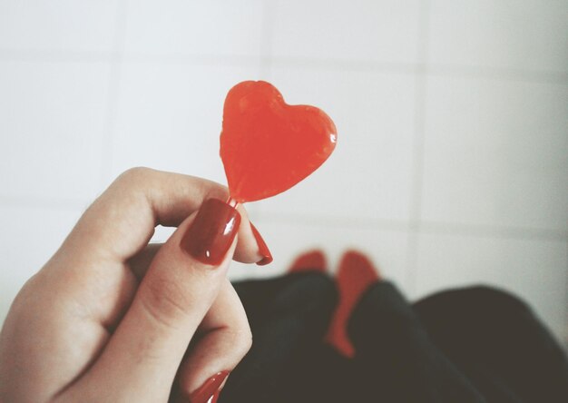 Foto mano tagliata di una donna che tiene caramelle a forma di cuore