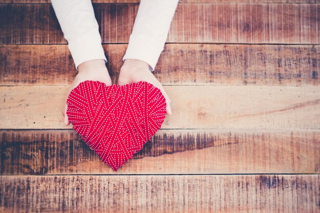 Foto mano tagliata di una donna che tiene una decorazione a forma di cuore al tavolo