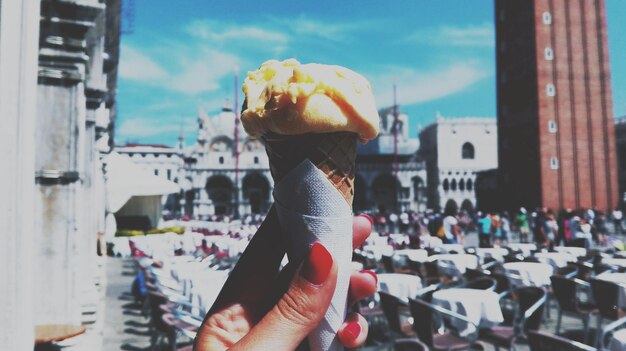 Photo cropped hand of woman holding ice cream cone against saint mark basilica