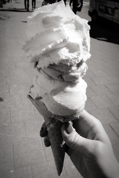 Foto mano tagliata di donna che tiene il gelato in strada