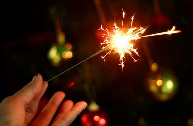 Photo cropped hand of woman holding illuminated sparkler at night