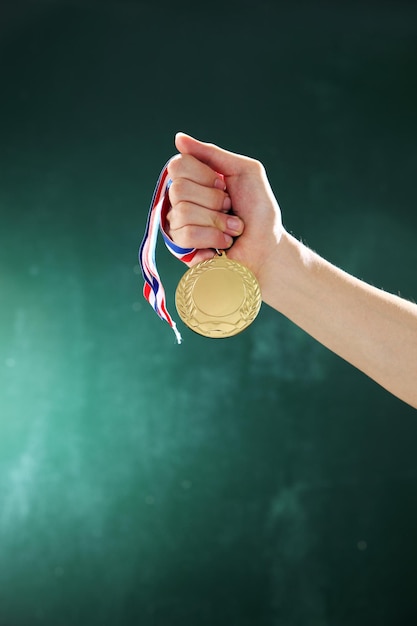 Foto mano tagliata di una donna che tiene una medaglia contro il muro