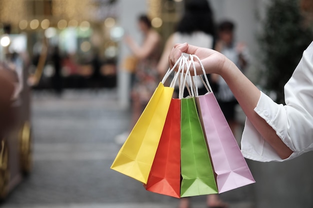 Cropped hand of woman holding multi colored shopping bags