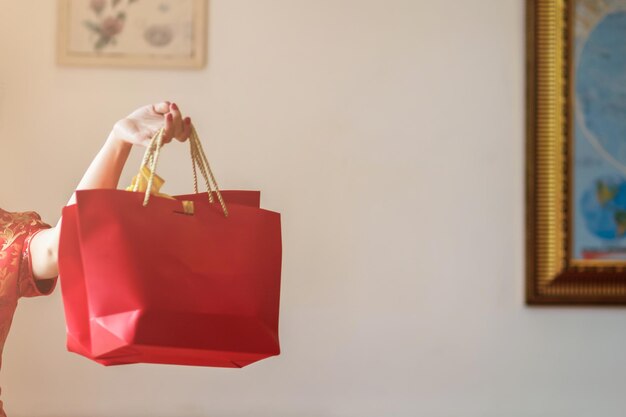 Photo cropped hand of woman holding paper bags against wall at home