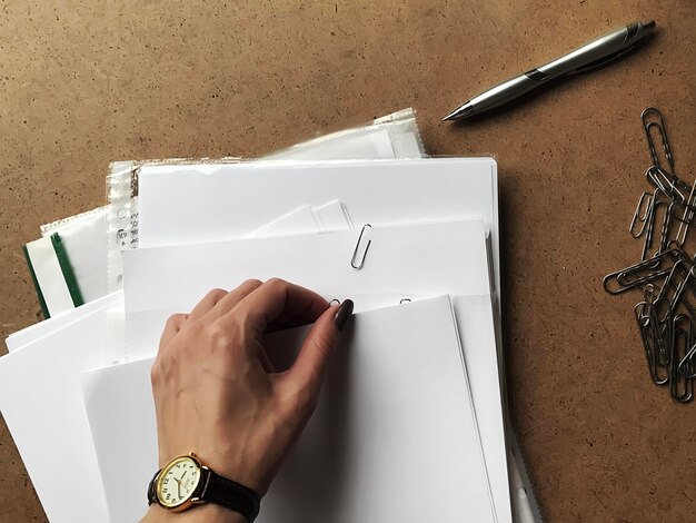 Photo cropped hand of woman holding papers on table