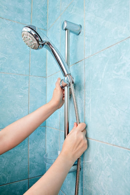 Cropped hand of woman holding shower head in bathroom