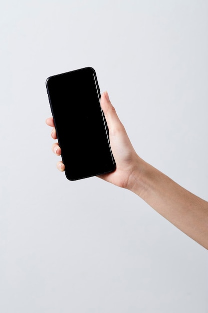 cropped hand of woman holding smart phone against white background