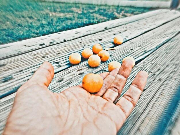 Foto mano tagliata di una donna che raccoglie frutta sul tavolo