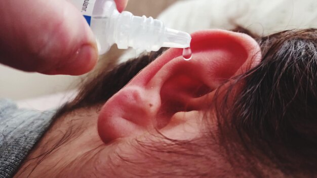 Photo cropped hand of woman pouring medicine in ear