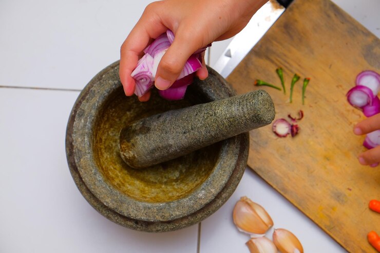 फोटो cropped hand of woman putting onions in mortar and pestle