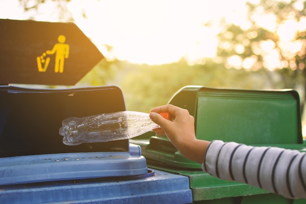 Foto mano tagliata di una donna che mette una bottiglia di plastica nel bidone della spazzatura