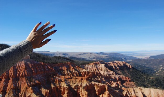 Photo cropped hand of woman reaching sky over mountains