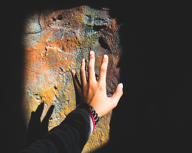 Foto la mano tagliata di una donna che raggiunge il muro