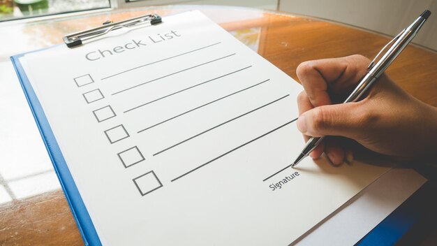 Cropped hand of woman signing on document