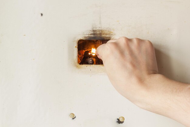 Cropped hand of woman starting boiler with lit matchstick