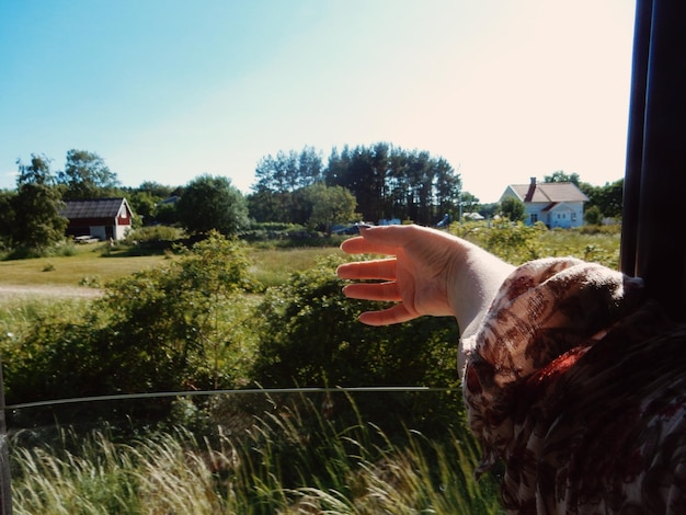 Foto mano tagliata di una donna che viaggia in un veicolo contro il cielo