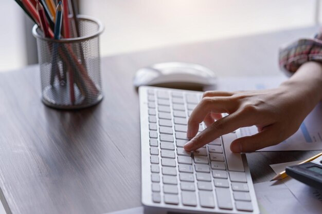 Foto mano tagliata di una donna che usa la tastiera di un computer sulla scrivania