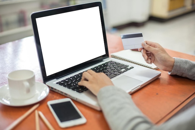 cropped hand of woman using laptop on table
