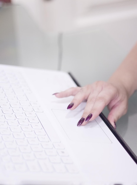 Cropped hand of woman using laptop on table