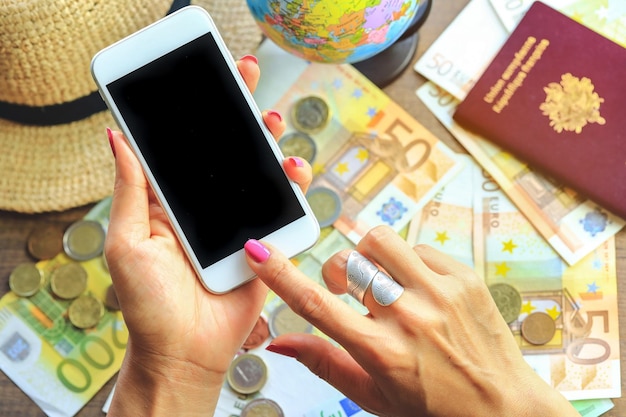 Photo cropped hand of woman using mobile phone against currency on table