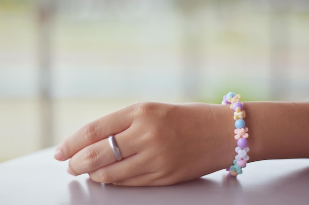 Photo cropped hand of woman wearing colorful bracelet at table
