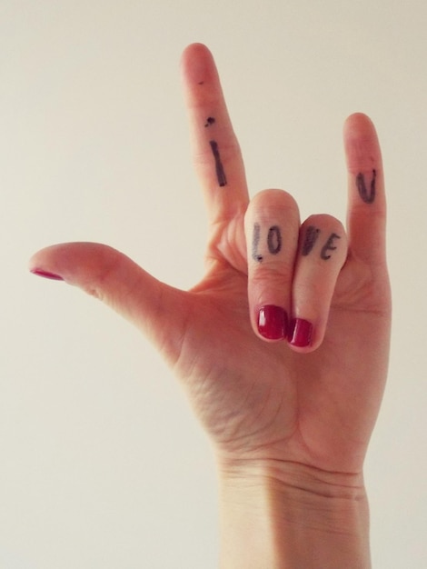Photo cropped hand of woman with i love you text over white background