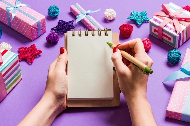 Cropped hand of woman writing in book on table