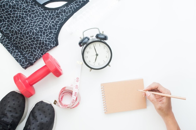 Photo cropped hand of woman writing in book with objects on table