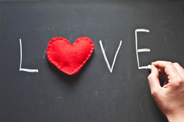 Foto la mano tagliata di una donna che scrive un testo d'amore sulla lavagna