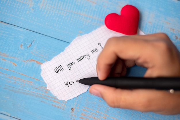 Cropped hand writing in paper over table