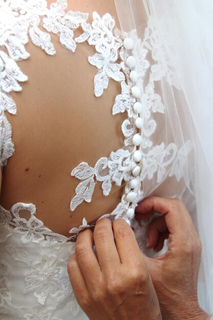 Cropped hands adjusting dress of bride