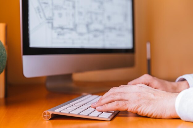 Photo cropped hands of architect using computer while sitting at table