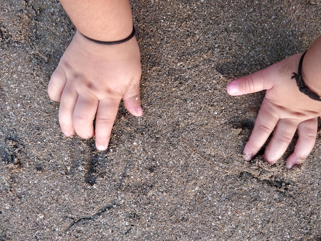 Foto mani tagliate di una bambina sulla sabbia della spiaggia