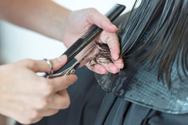 cropped hands of barber cutting woman hair at salon