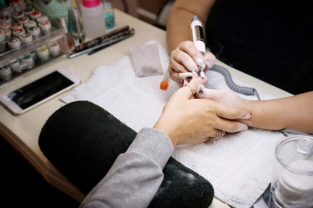 Cropped hands of beautician doing manicure of woman