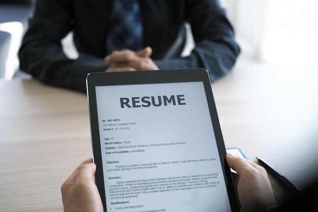 Photo cropped hands of business person holding digital tablet showing resume while interviewing candidate