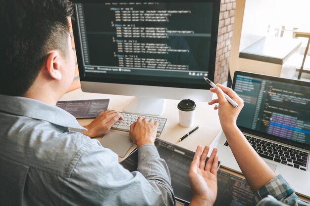 オフィスで同僚にコンピューターでコーディングを説明するビジネスマンの切断された手