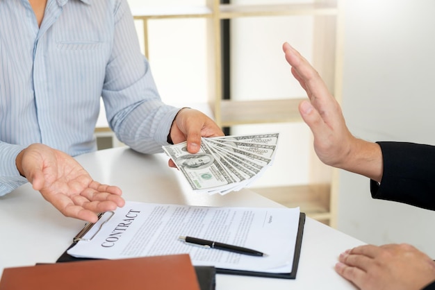 Photo cropped hands of businessman refusing bribe from male coworker in office