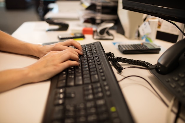 Cropped hands of businesswoman using computer keyboard at office