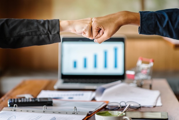 Photo cropped hands of businesswomen fist bumping in office