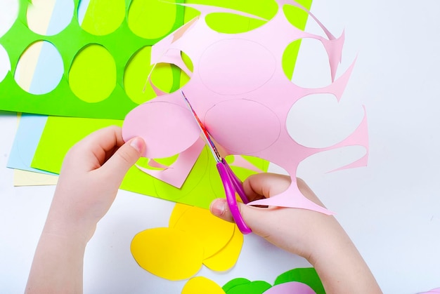 cropped hands of child cutting papers on table