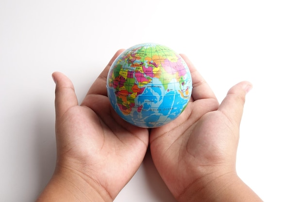 Cropped hands of child holding globe against white background