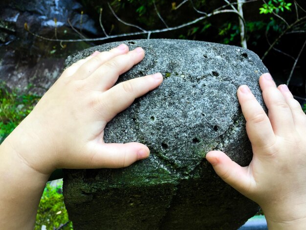 Photo cropped hands of child touching rock