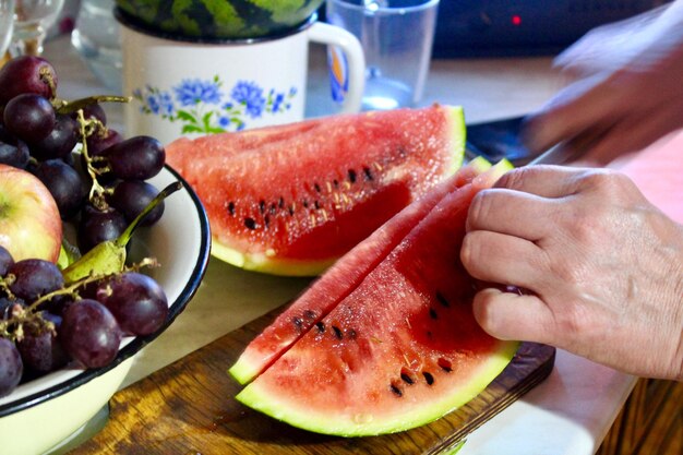 Cropped hands chopping watermelon on table