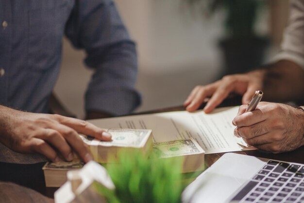 Cropped hands of colleagues signing document on desk in office