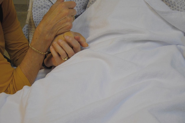 Cropped hands of couple holding hands in hospital