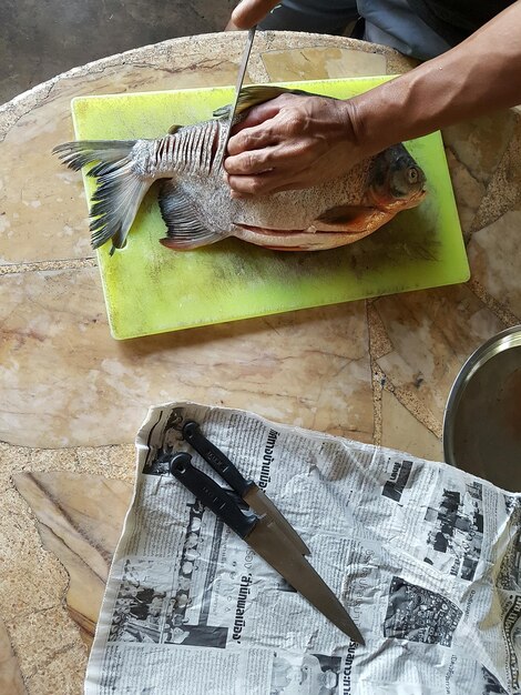 Photo cropped hands cutting fish on table